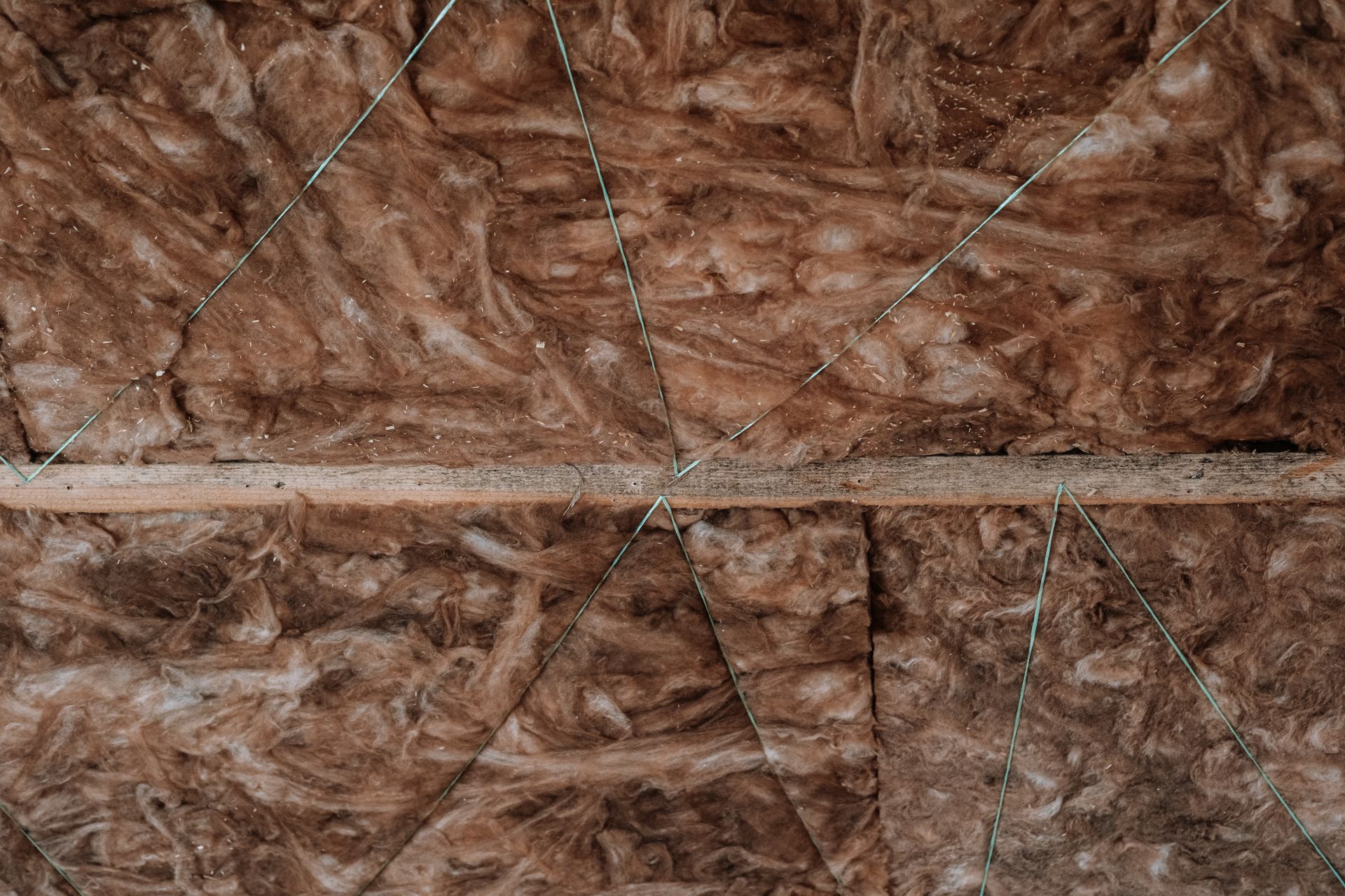 Close-up of rough brown textured surface with intersecting seams and faint diagonal lines