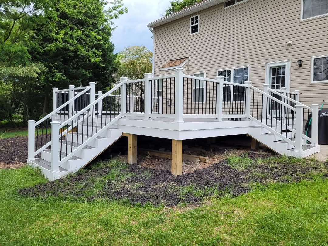Elevated white wooden deck with stairs attached to a beige house in a grassy yard