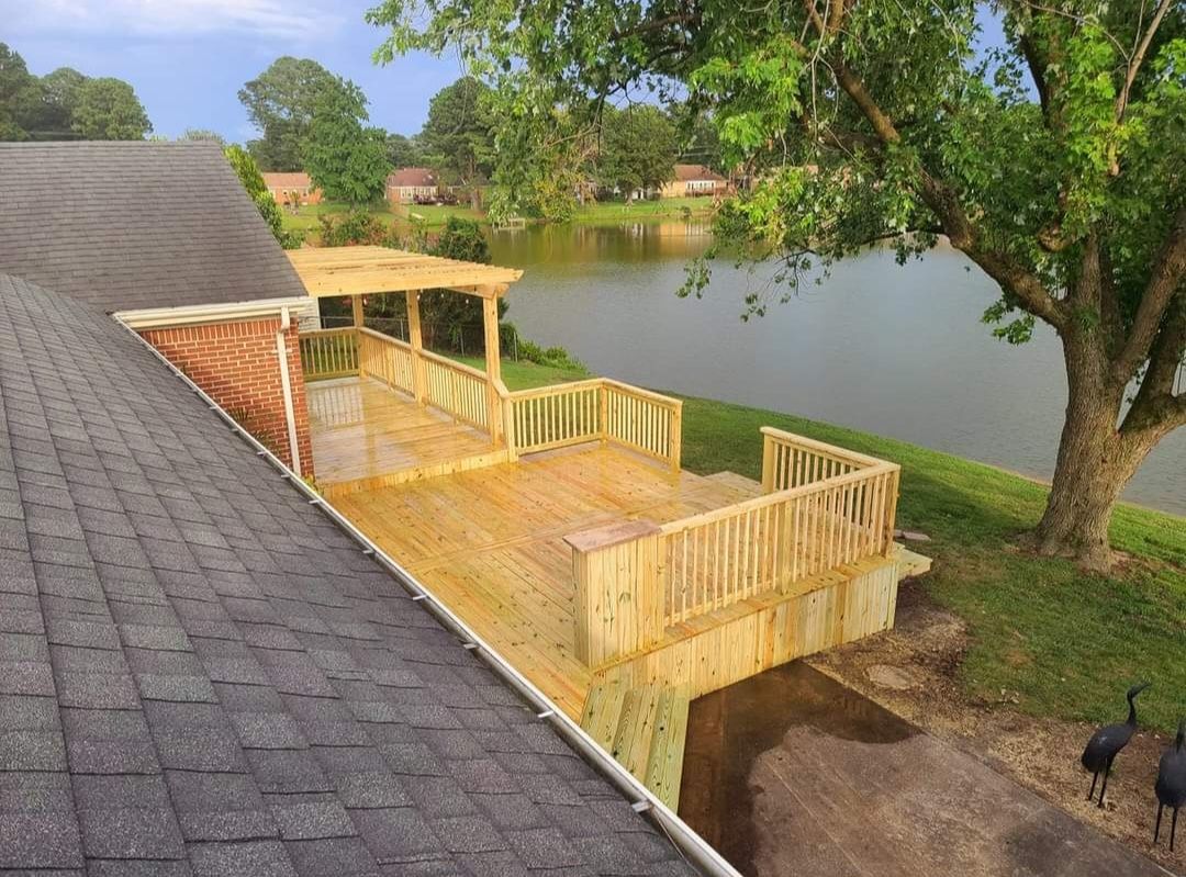Yellow deck beside a lake under trees, viewed from a shingled roof