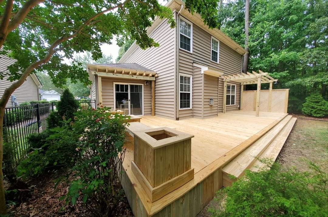 Wooden deck and stairs added to a beige house in a leafy backyard