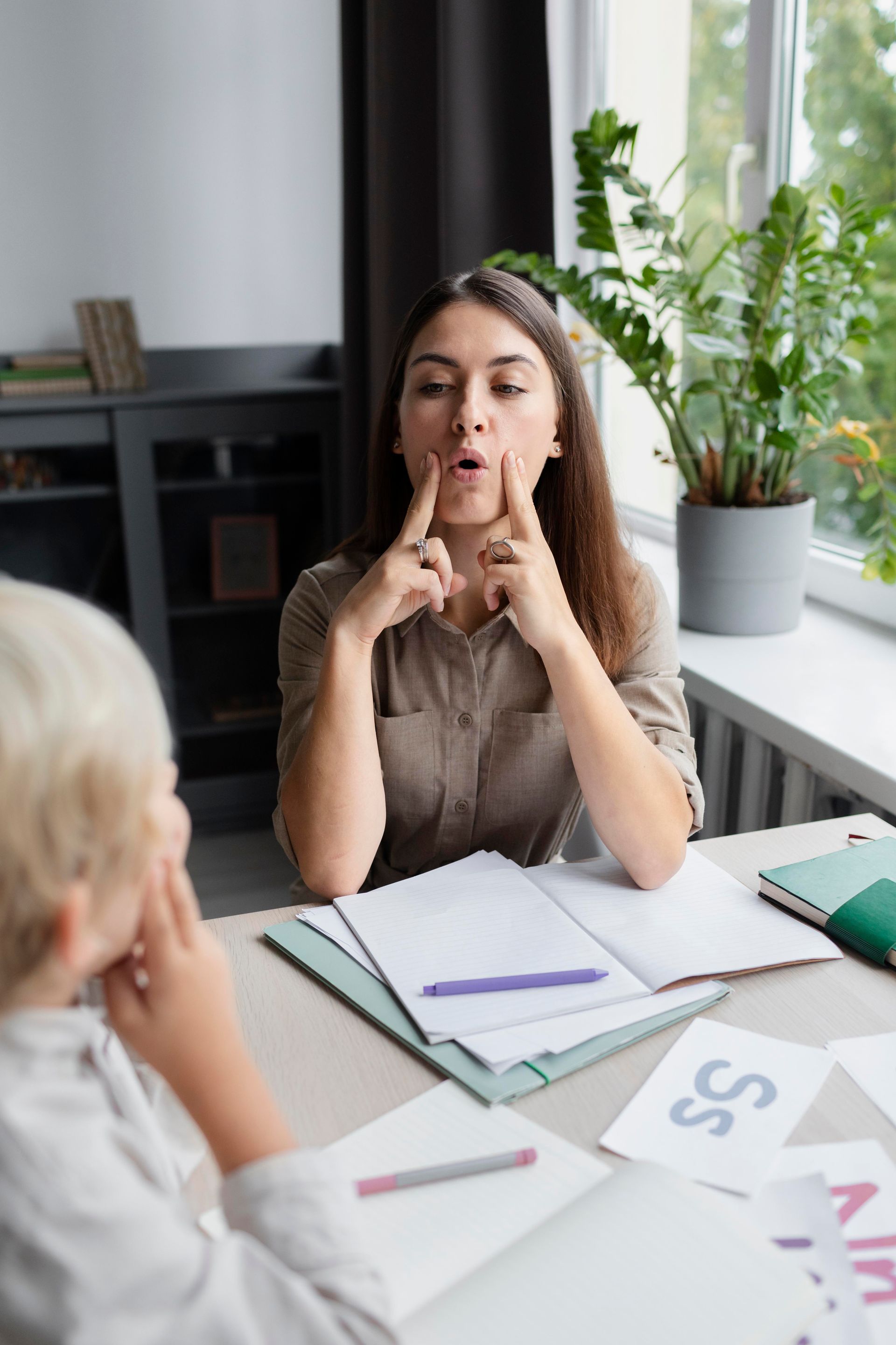 A woman is sitting at a table talking to a boy in sign language.