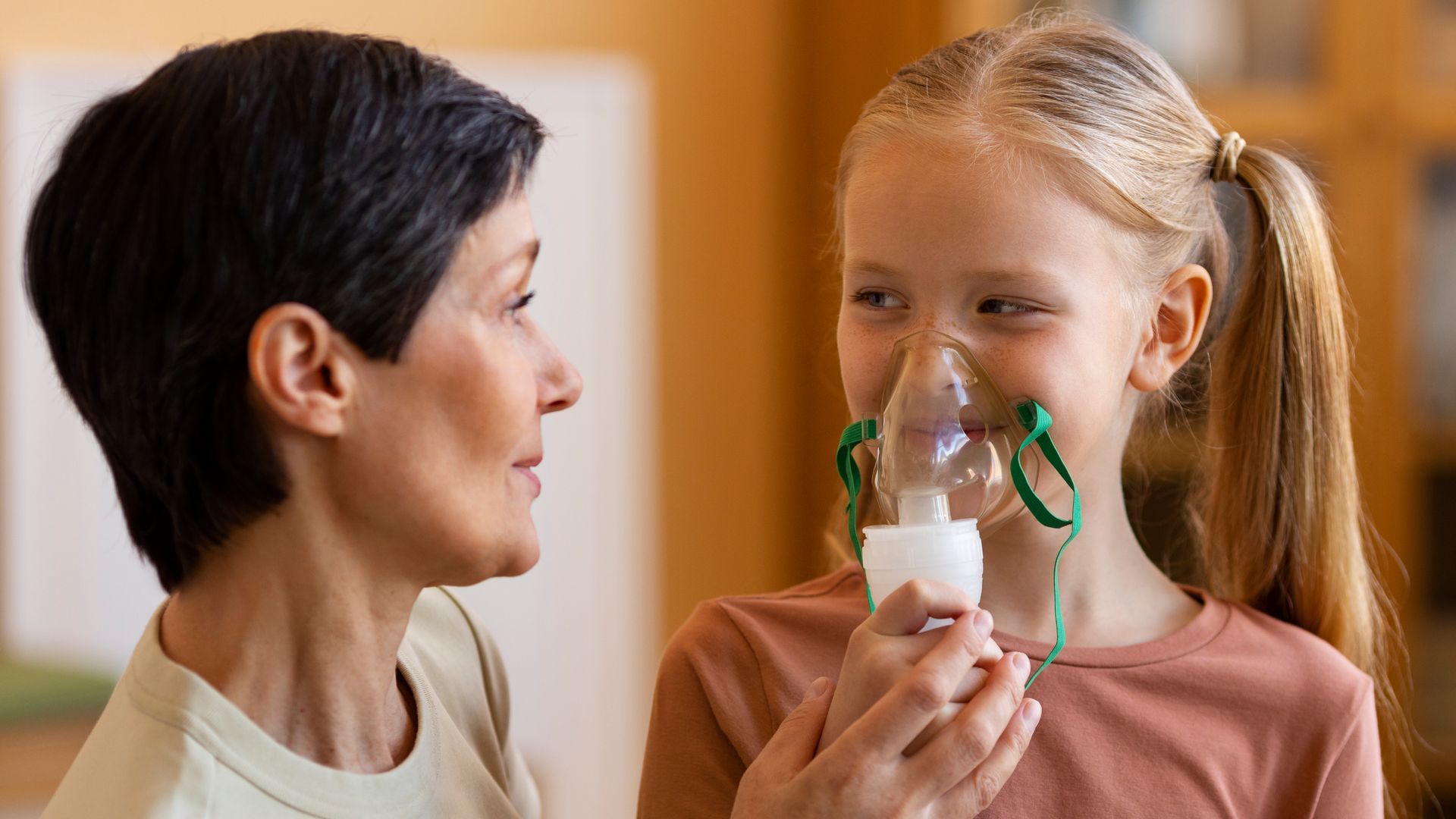 A woman is giving a little girl an oxygen mask.
