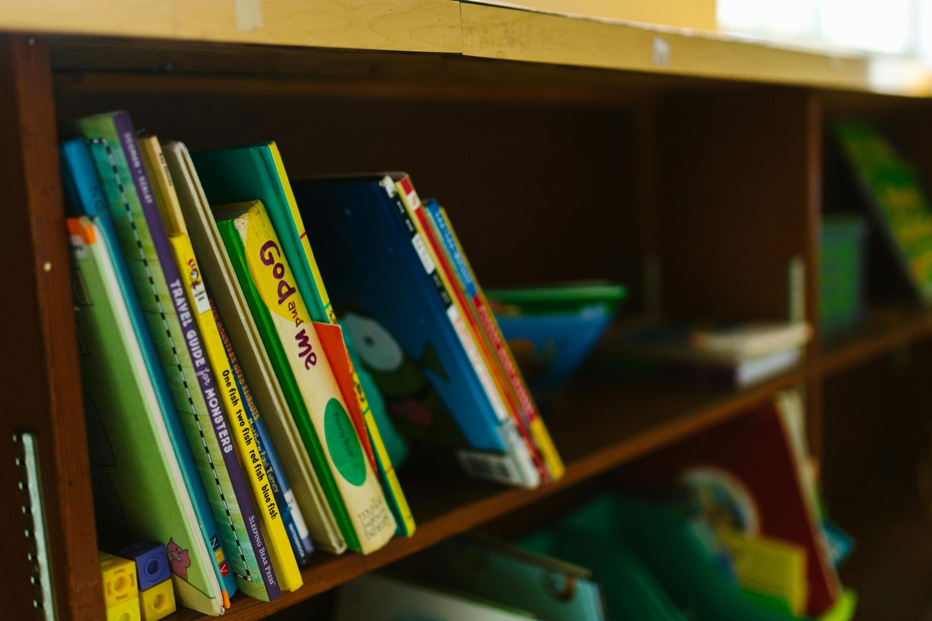 Colorful children’s books lined on a wooden shelf in a library or classroom