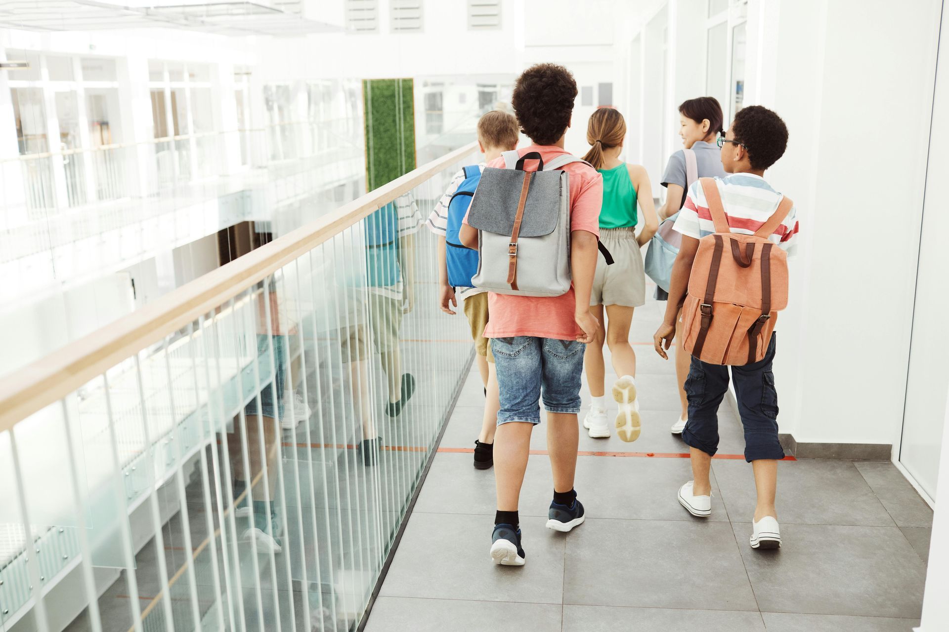 Children walking down a bright school hallway with backpacks