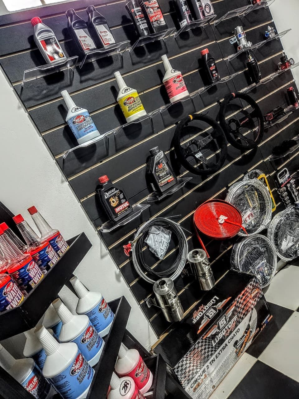 Pared de productos y accesorios para el cuidado del automóvil en estantes de paneles ranurados en un pasillo de la tienda.