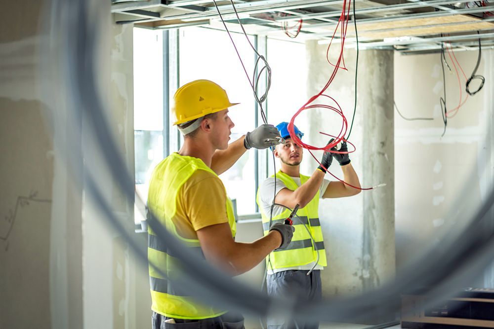 Two construction workers are working on a ceiling in a building.