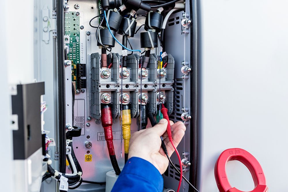 A person is working on an electrical box with a multimeter.