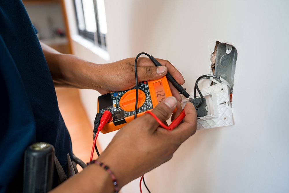 A person is using a multimeter to test a light switch.
