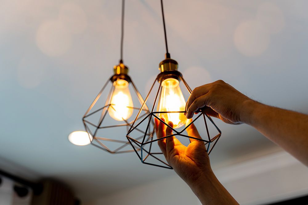 A person is changing a light bulb in a pendant light.