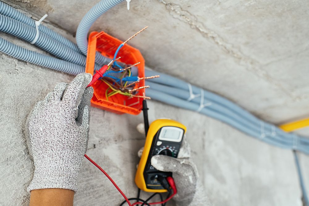 A person is using a multimeter to test an electrical box.