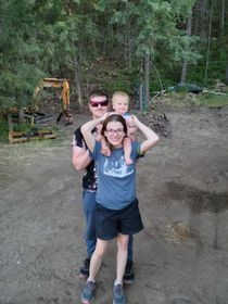 A man and a woman are holding a baby on their shoulders.