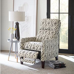 Patterned armchair with matching ottoman in a bright living room beside a lamp and side table.