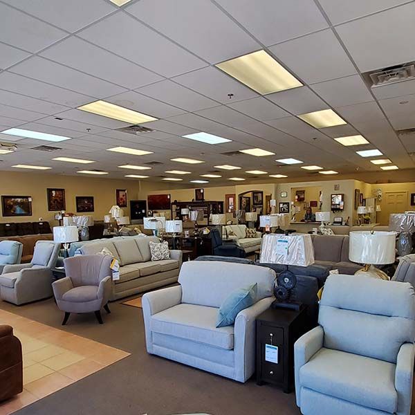 Furniture showroom with rows of sofas and armchairs under bright ceiling lights