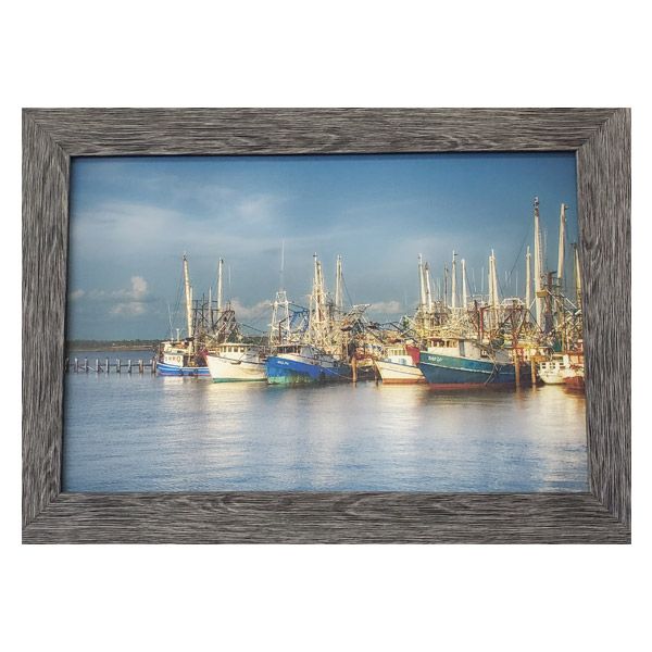 Harbor scene with colorful fishing boats and masts on calm water under a cloudy blue sky