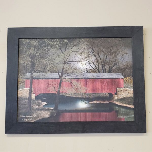 Framed painting of a red covered bridge over calm water with bare trees in winter