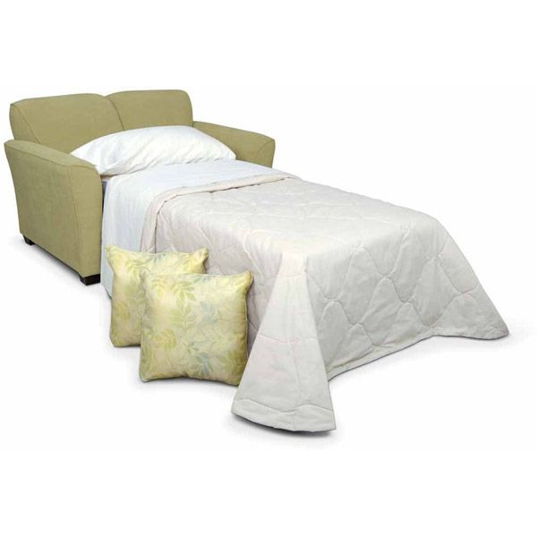 Green armchair beside a white-covered bed with pillows in a plain studio setting