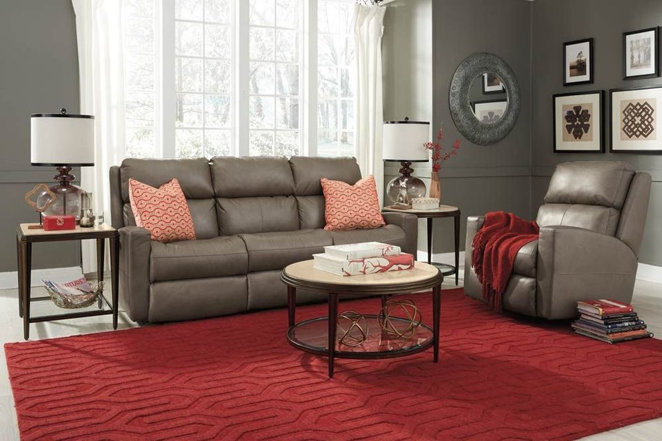 Modern living room with gray sofa, recliner, red rug, round coffee table, and large windows