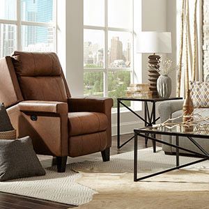 Cozy living room with a brown recliner, glass coffee table, and large windows overlooking a city view