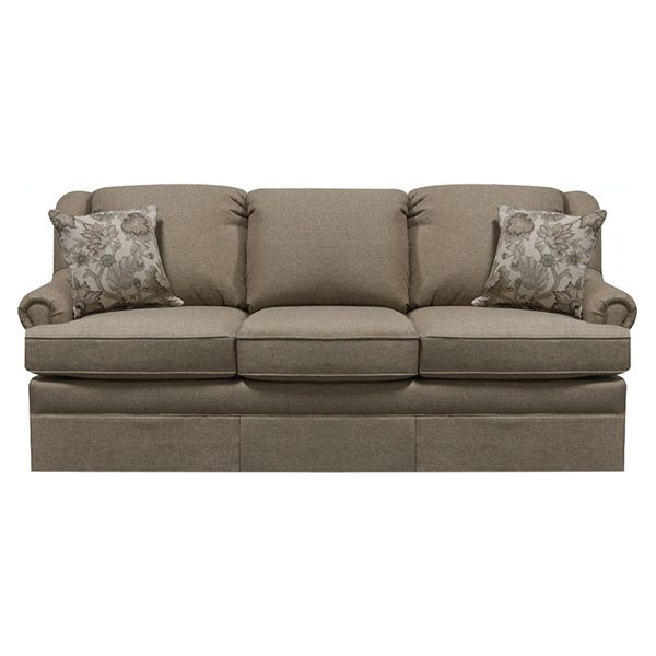 Taupe upholstered sofa with floral throw pillows and a skirted base