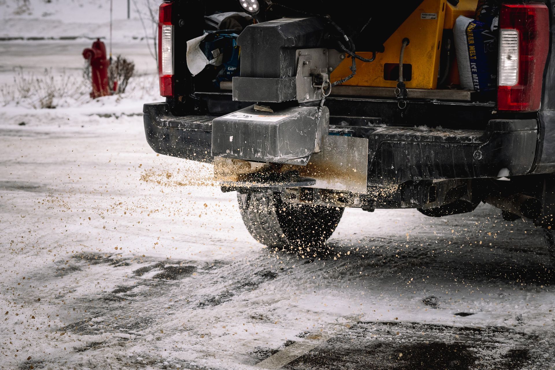 A truck is spreading salt on a snowy road.