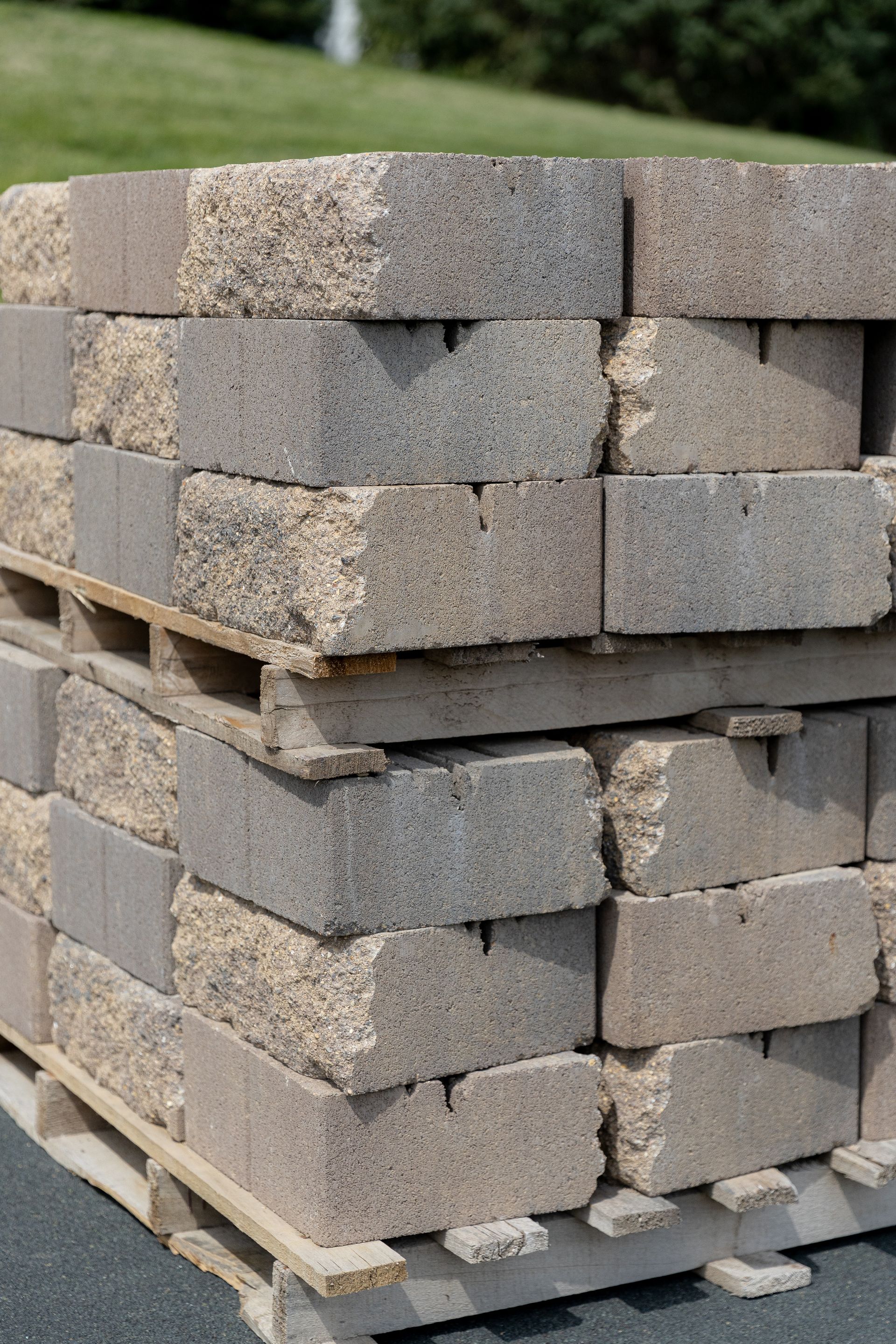 Pallet stacked with rectangular, light-colored concrete blocks, outdoors.