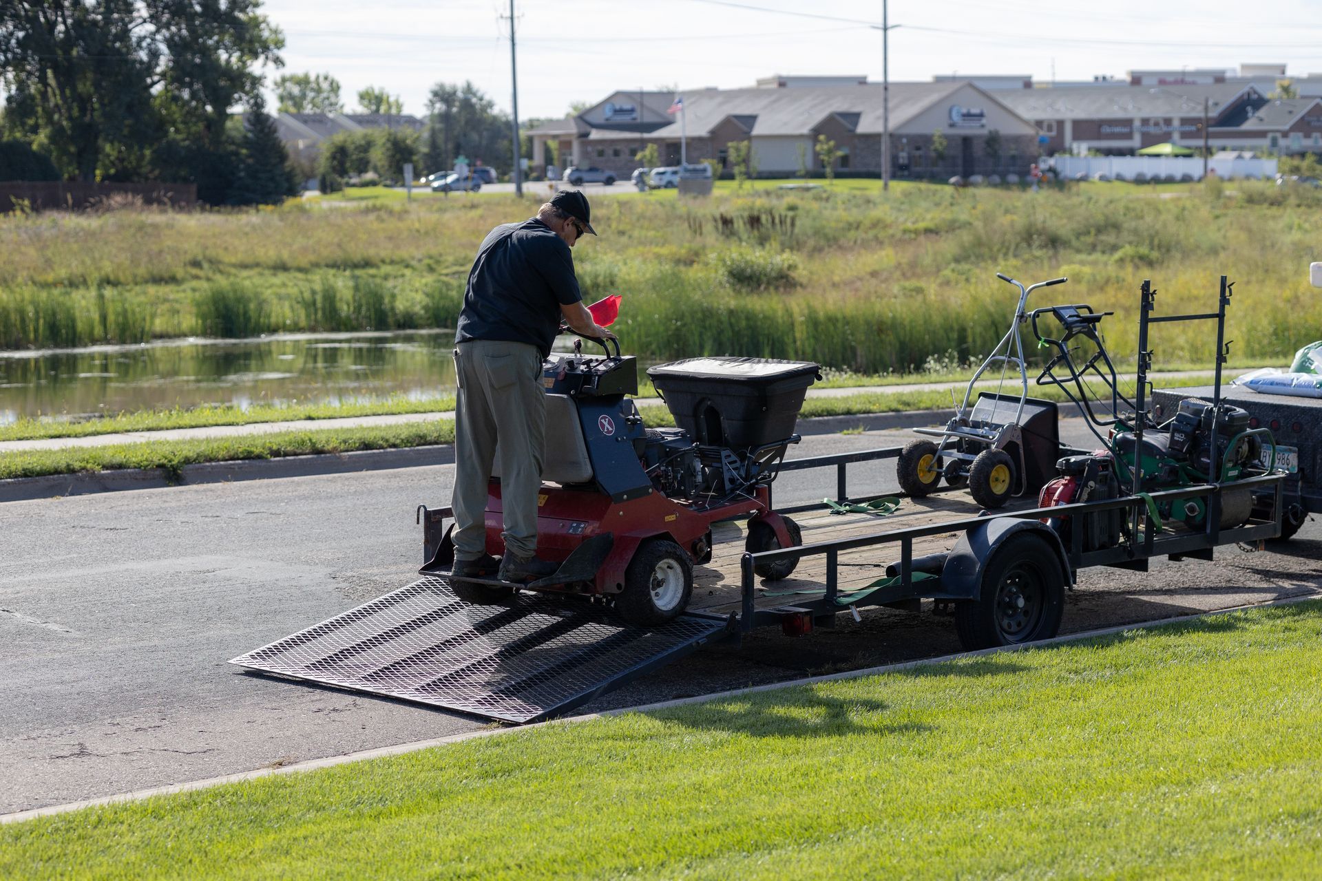 A man is loading a lawn mower on a trailer.
