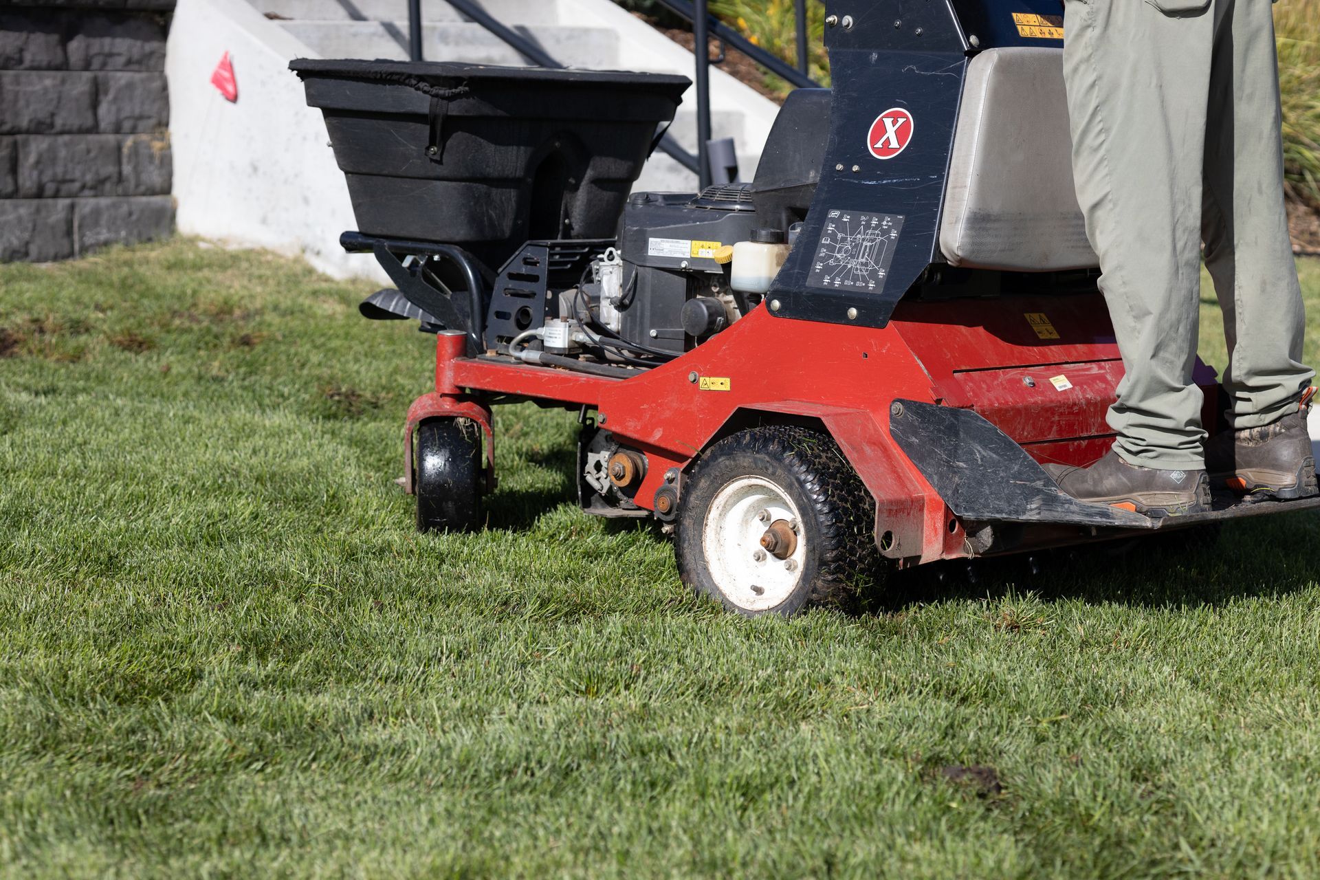A person is riding a lawn mower on a lush green lawn.