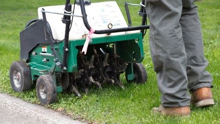 A person is using a machine to aerate a lawn.