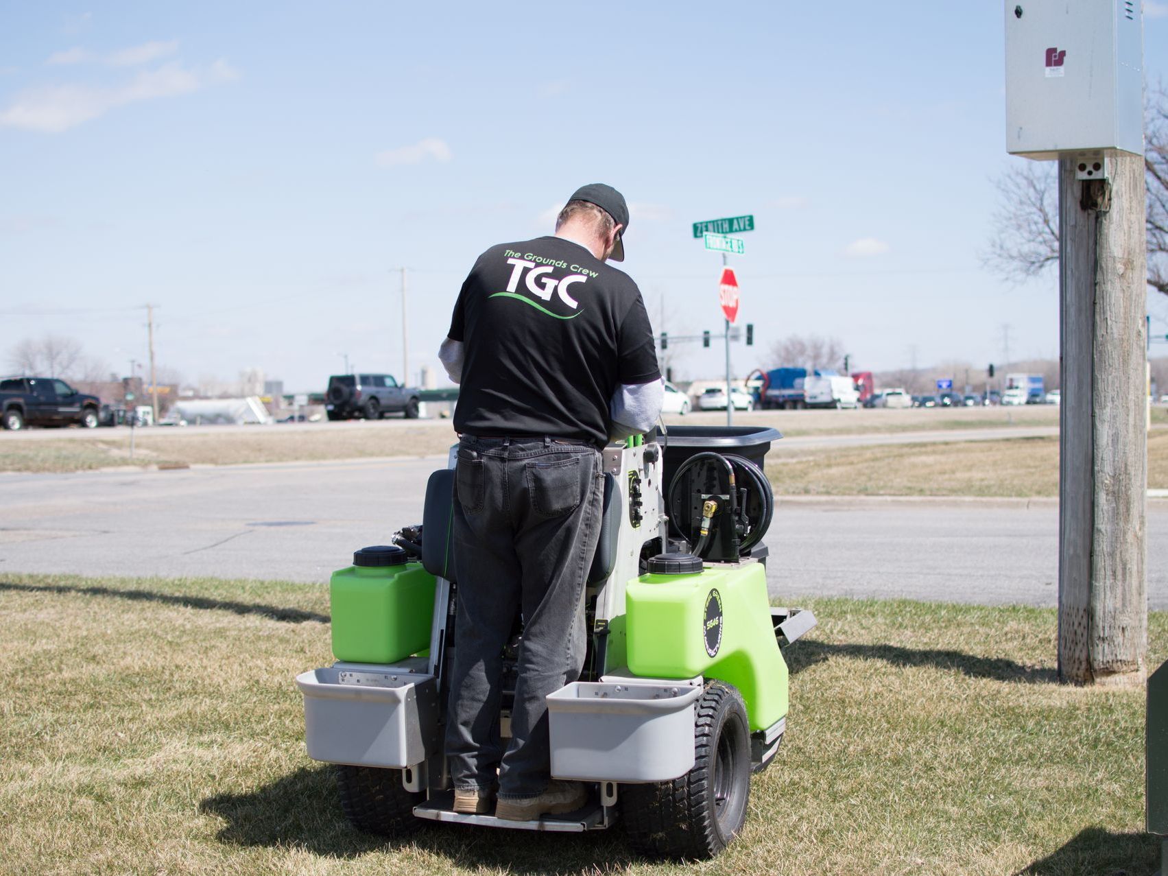 A man is riding a green lawn mower in a grassy field.