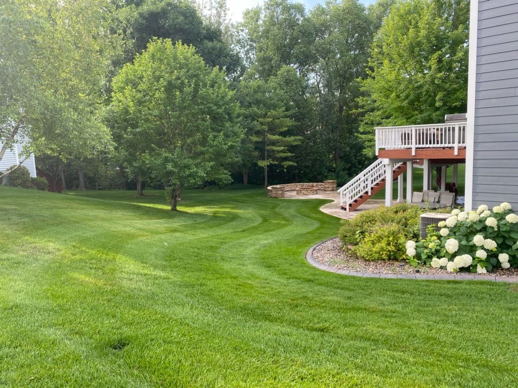 TGC lawn care displaying a lush green yard with a house and a deck in the background