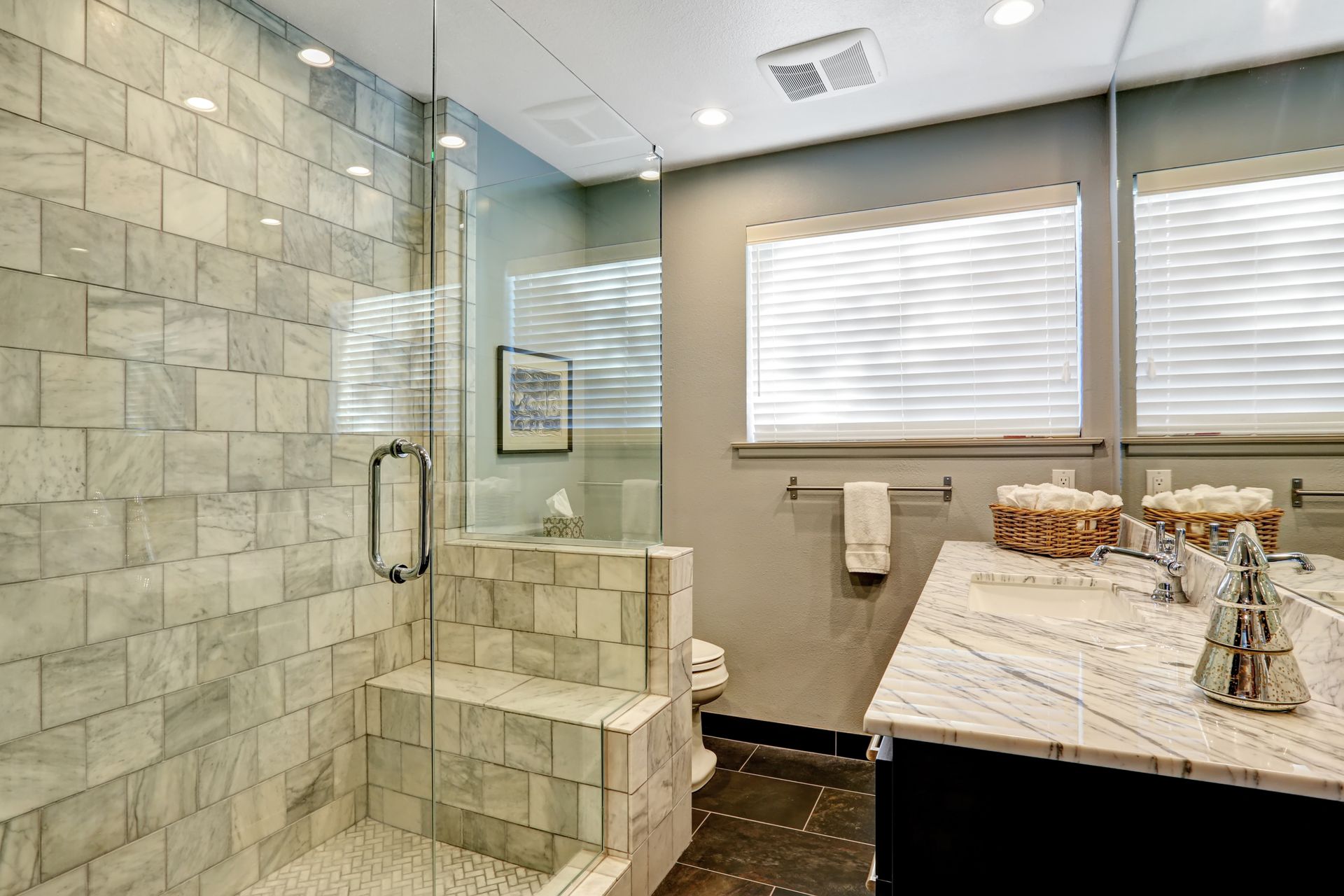 Bathroom with marble shower, gray walls, vanity with mirror, and a window.