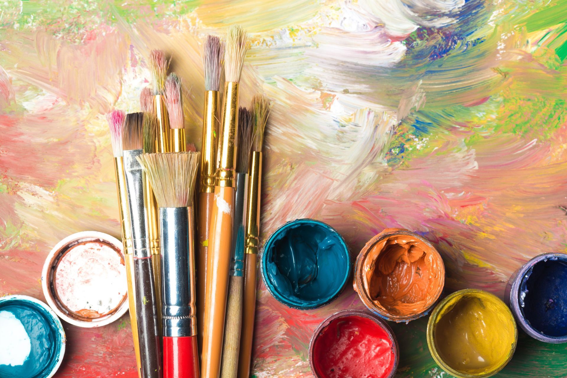 A bunch of paint brushes and bowls of paint on a palette.