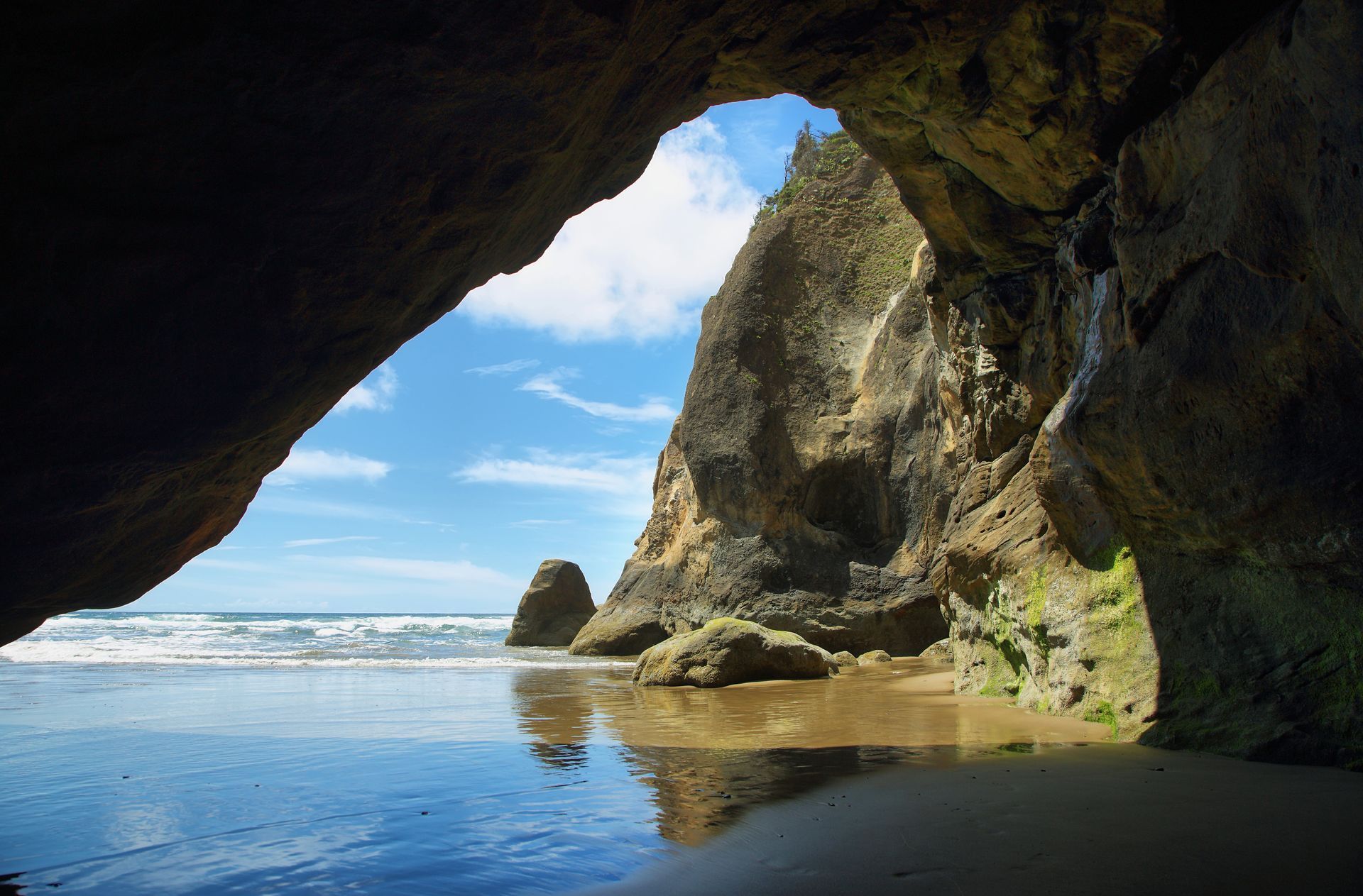 A view of a beach from inside a cave.