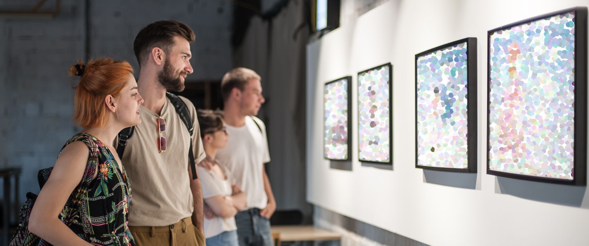 A group of people are looking at paintings in a museum.