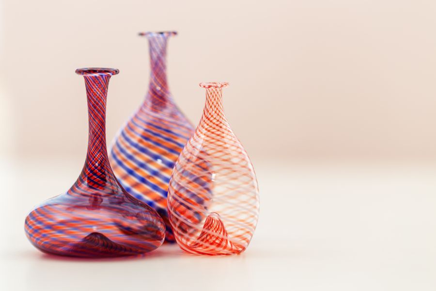 Three colorful glass vases are sitting next to each other on a table.