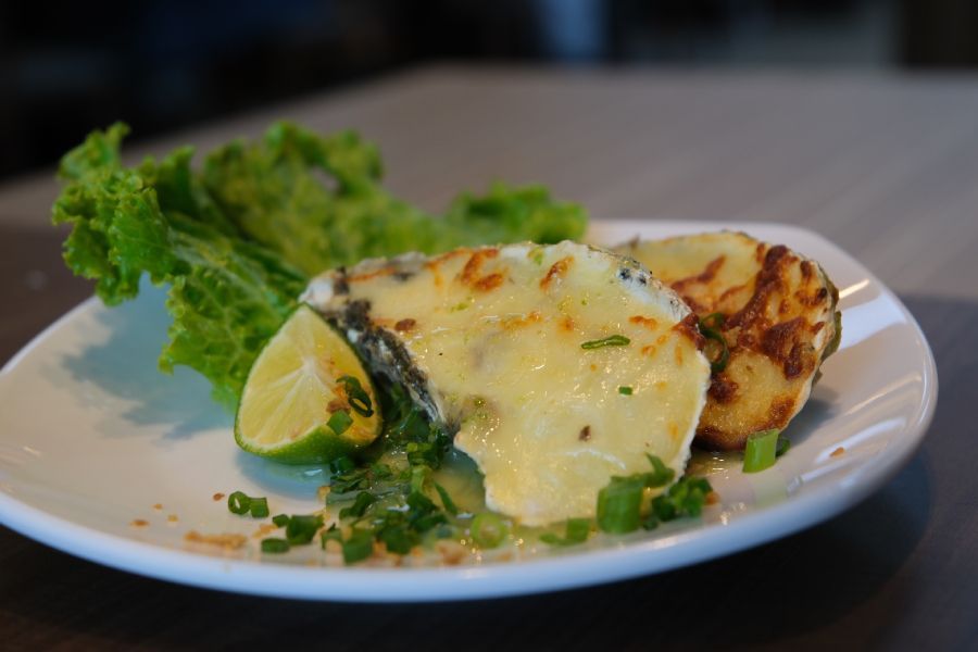 A white plate topped with a piece of cheese , potatoes and lettuce.