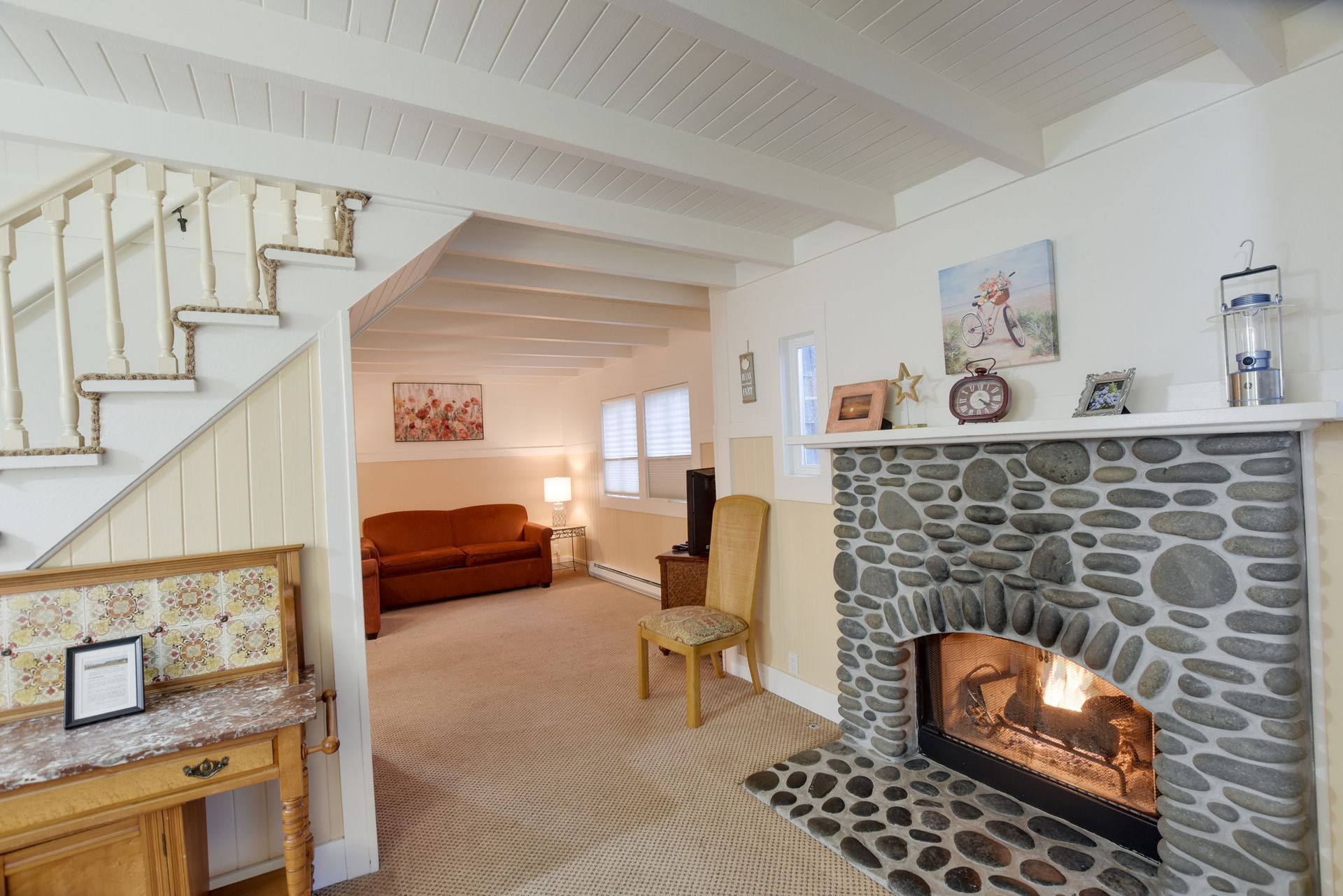 A living room with a stone fireplace and stairs