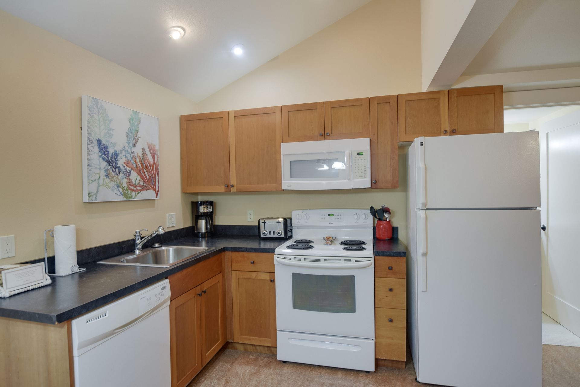 A kitchen with a stove , refrigerator , dishwasher , microwave and sink.