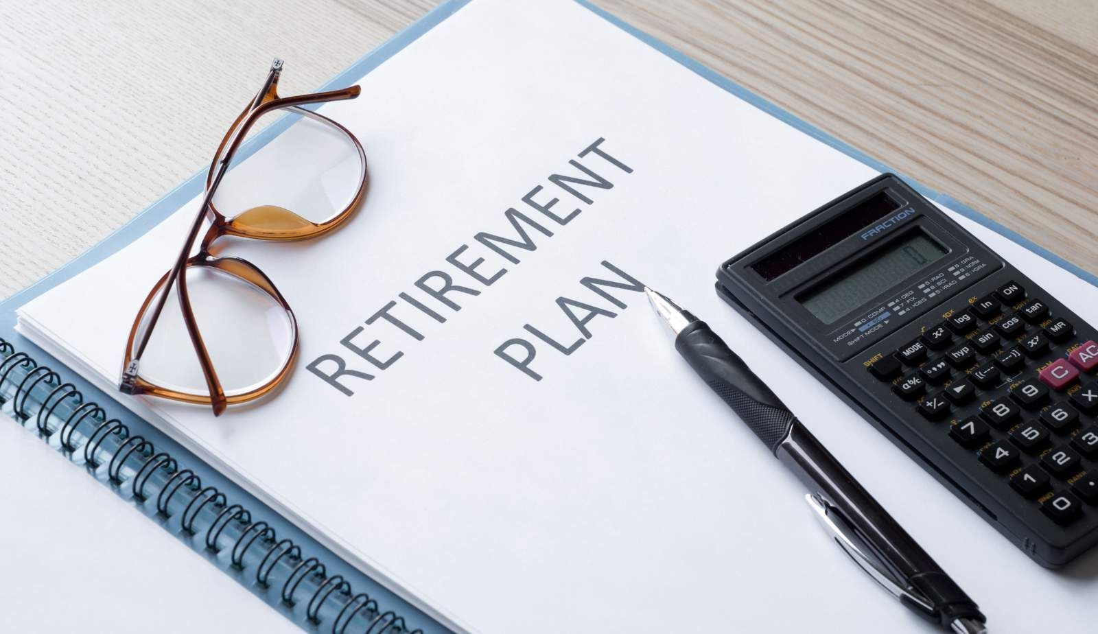A retirement plan is written on a piece of paper next to a pen and calculator.