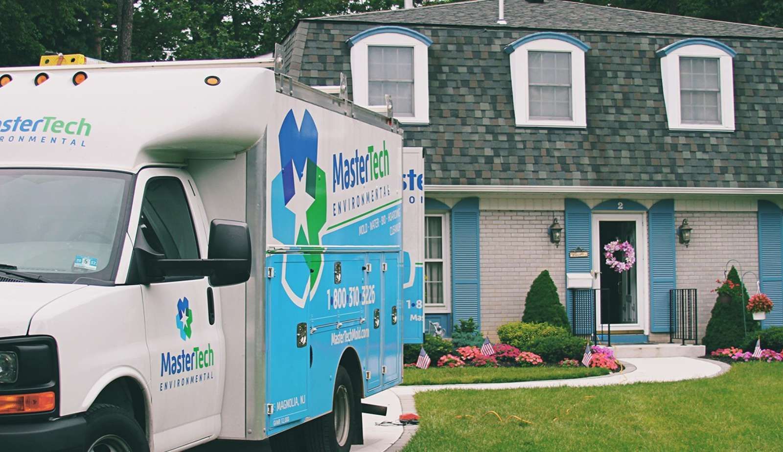 A Mastertech Environmental truck is parked in front of a house.