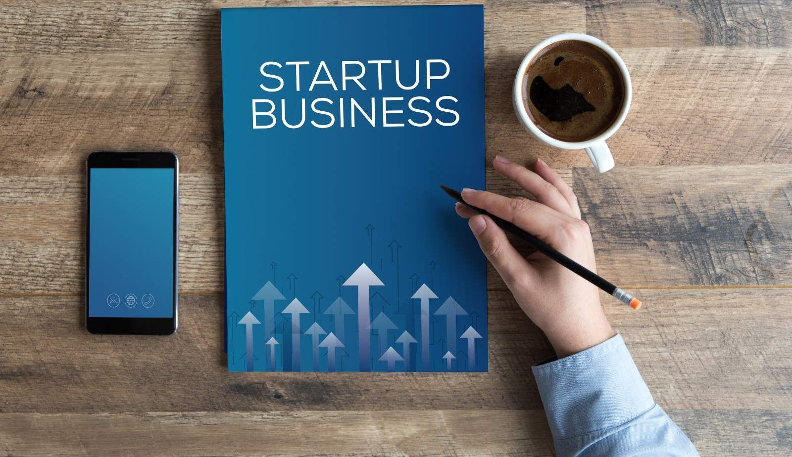 A person is writing on a piece of paper that says startup business.