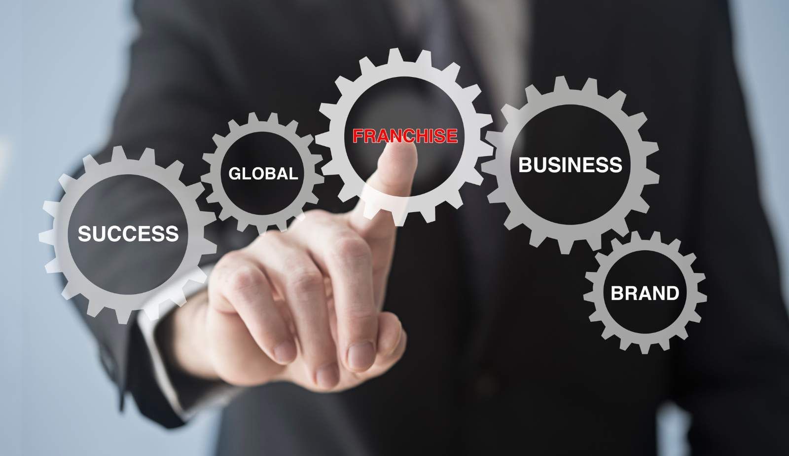 A man in a suit is holding a gear with the word progress on it.