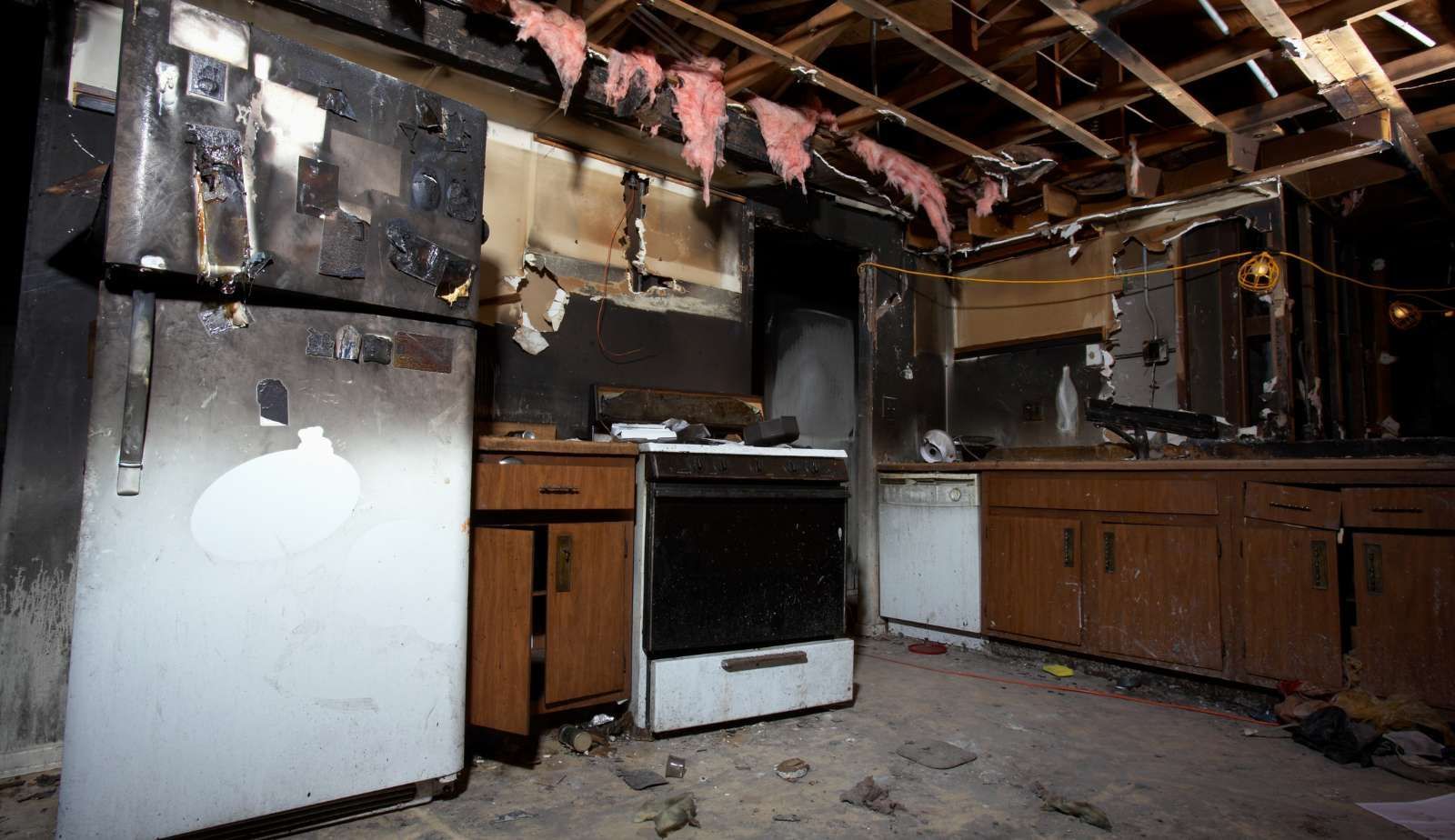 A kitchen in an abandoned house with a refrigerator , stove , and dishwasher.