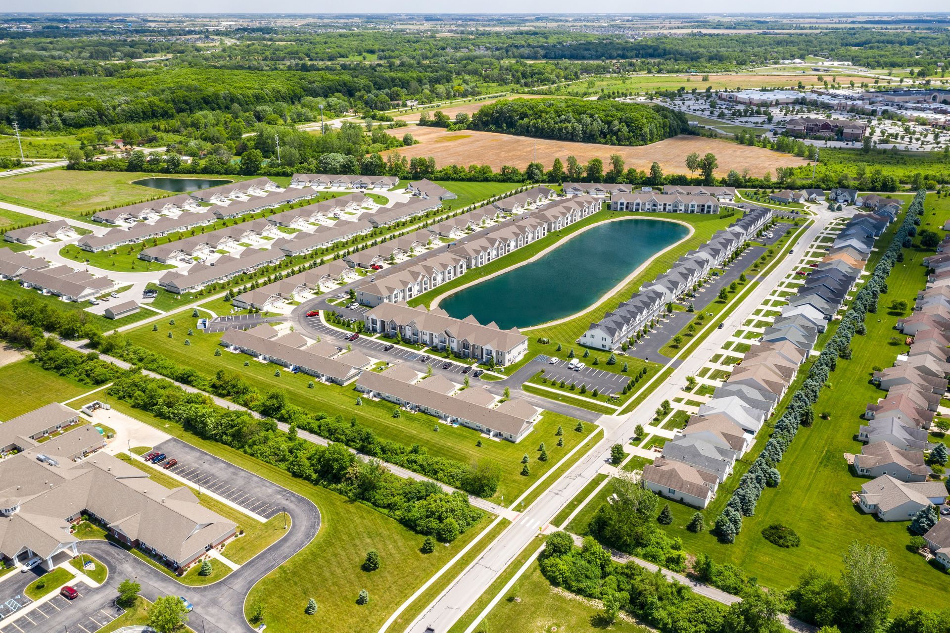Aerial view of a suburban neighborhood with rows of houses surrounding a lake and green spaces.