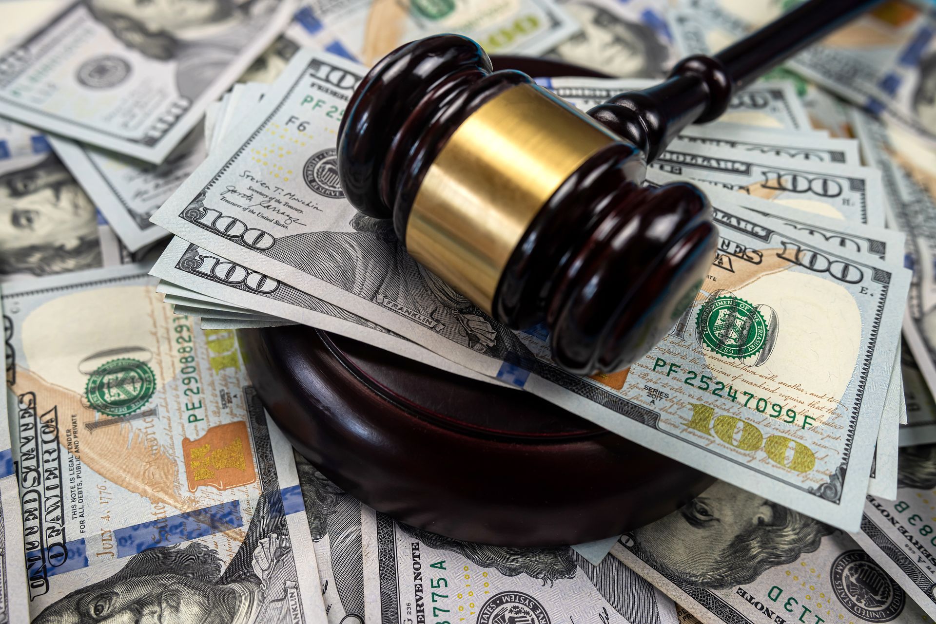 Gavel on a stack of hundred-dollar bills, suggesting legal or financial themes.