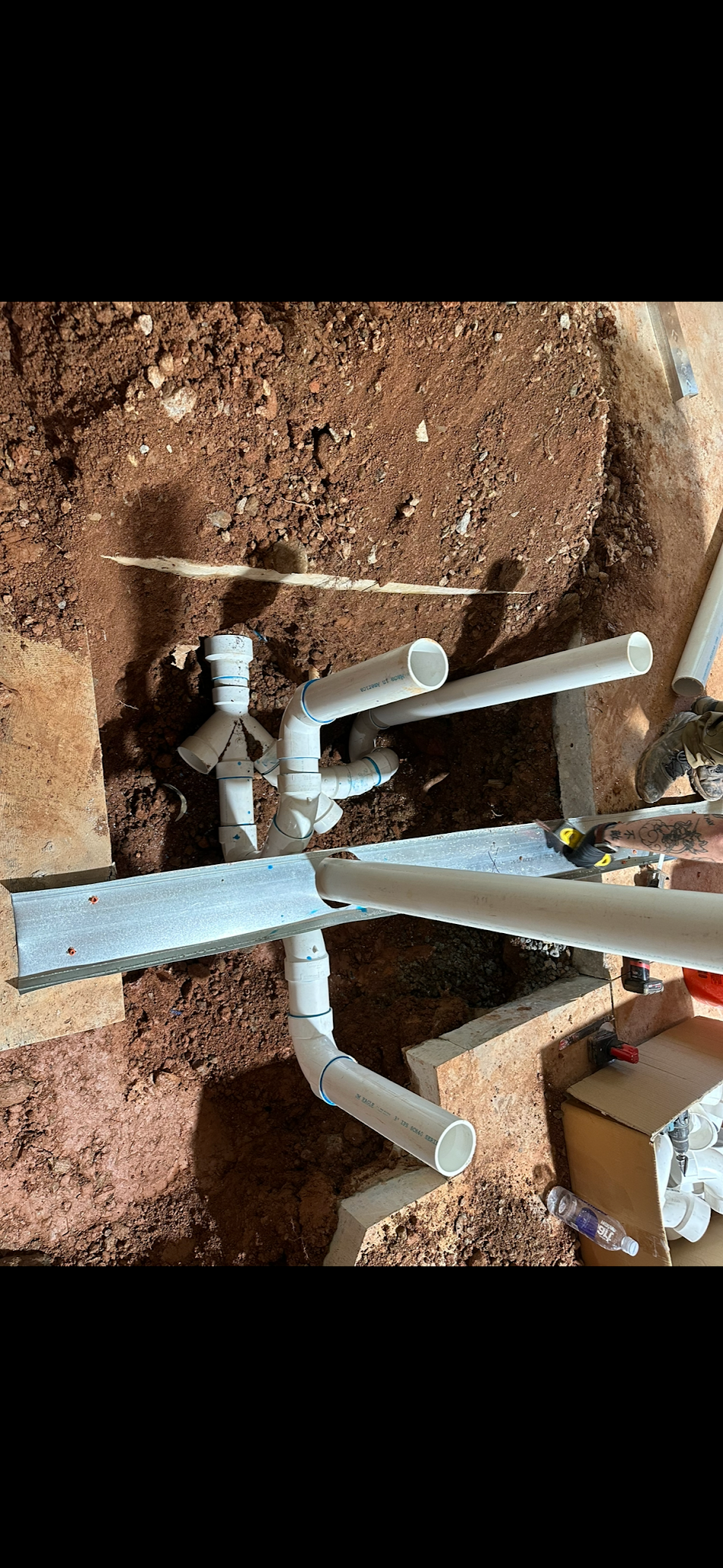 A person is working on a pipe in the dirt.
