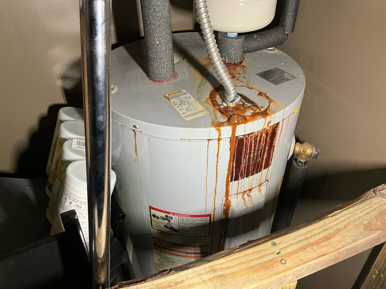 Leaking water heater with brown streaks, located indoors.