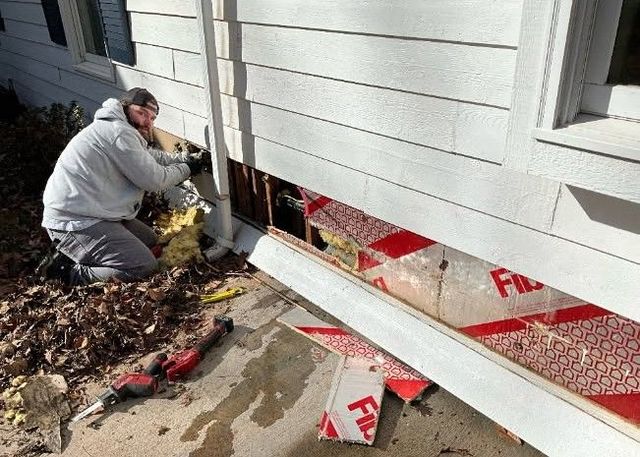 Leaking water heater, rust-colored streaks running down its side in an enclosed room.