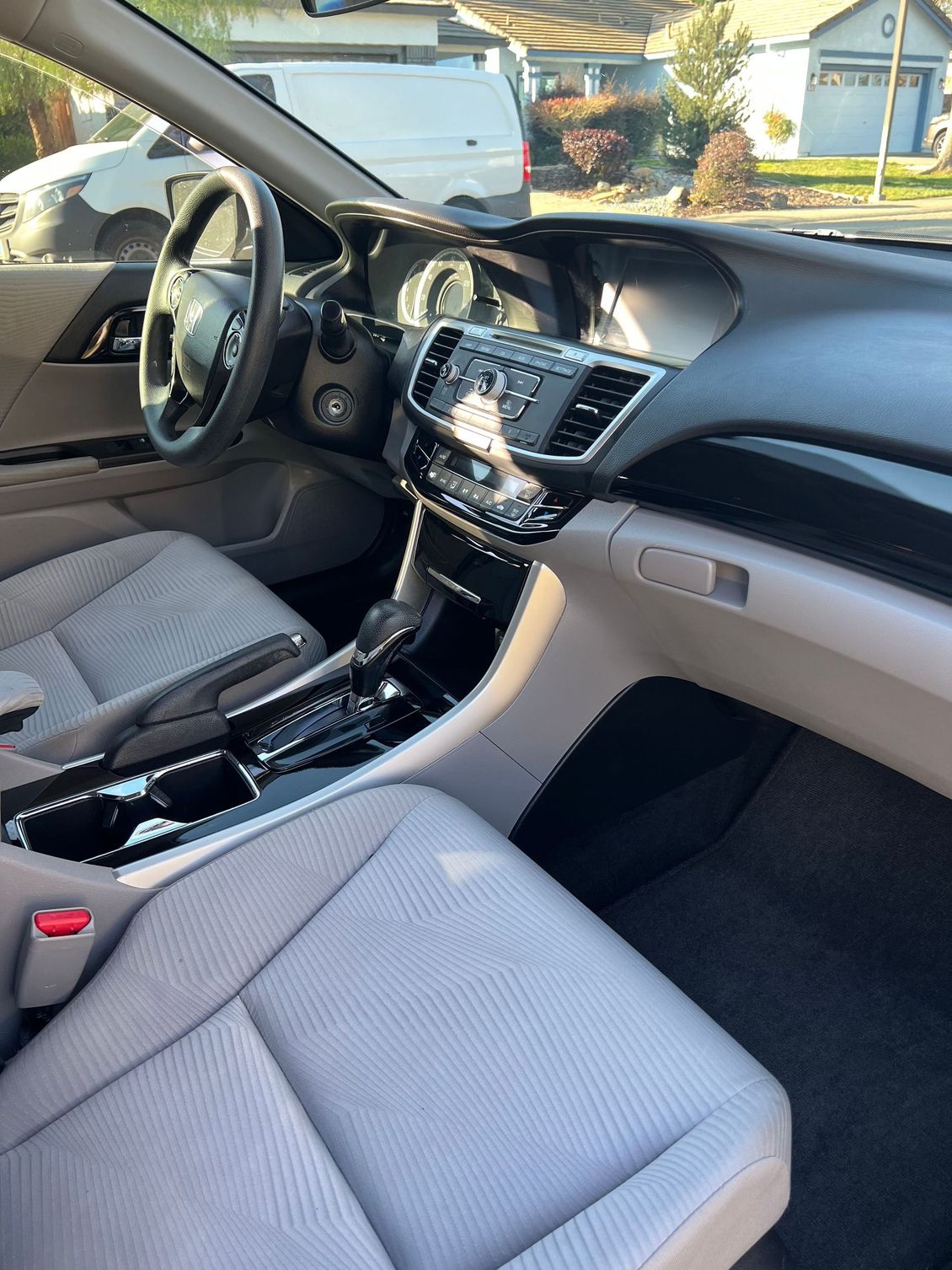 Car interior with gray seats, dashboard, and center console, viewed from the passenger side.