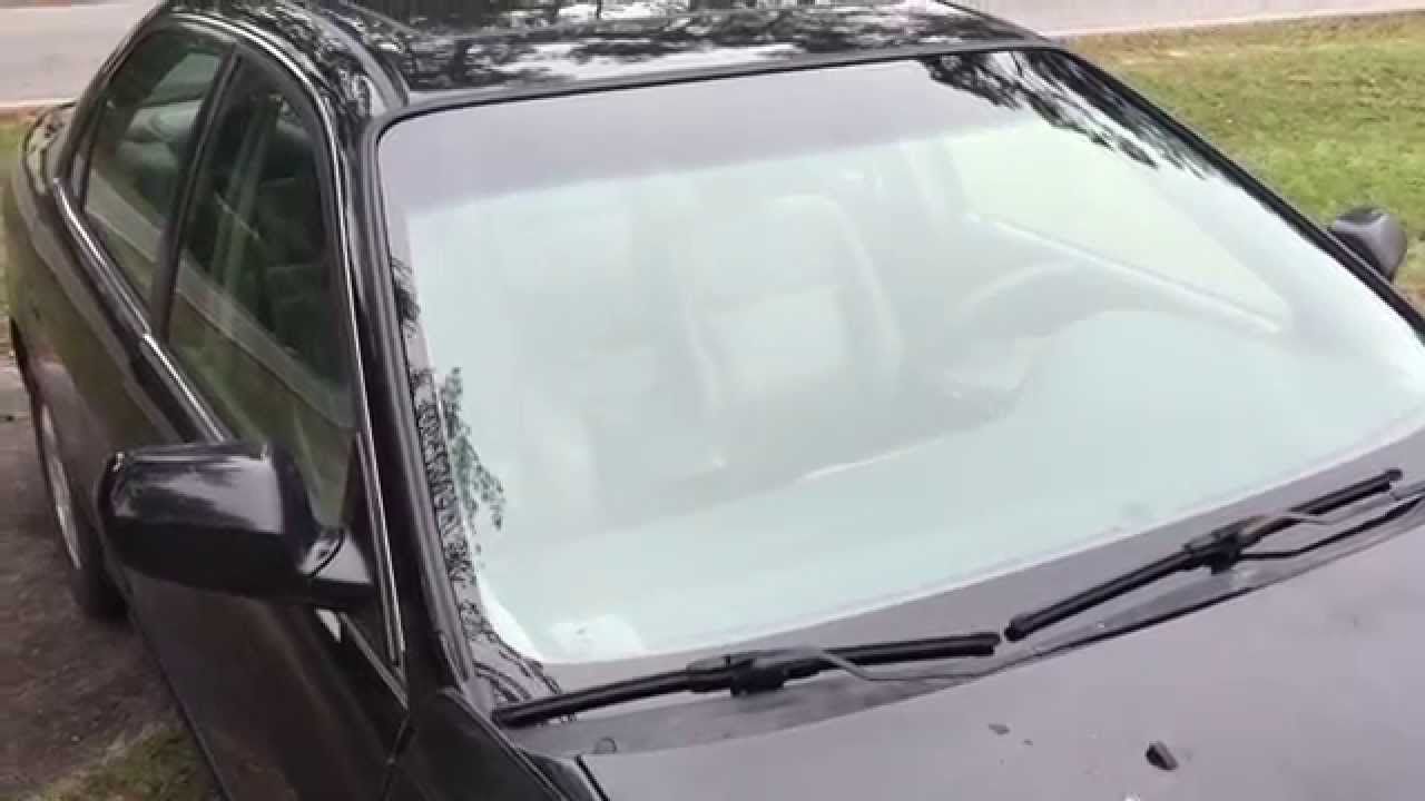Une voiture noire avec une galerie de toit dessus est garée dans une allée.